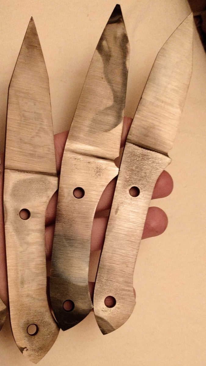 Drei Messerklingen nach dem Härten mit Härteschutzfolie - zu beachten die Beschädigungen der Folie am Griffende und an der Messerspitze